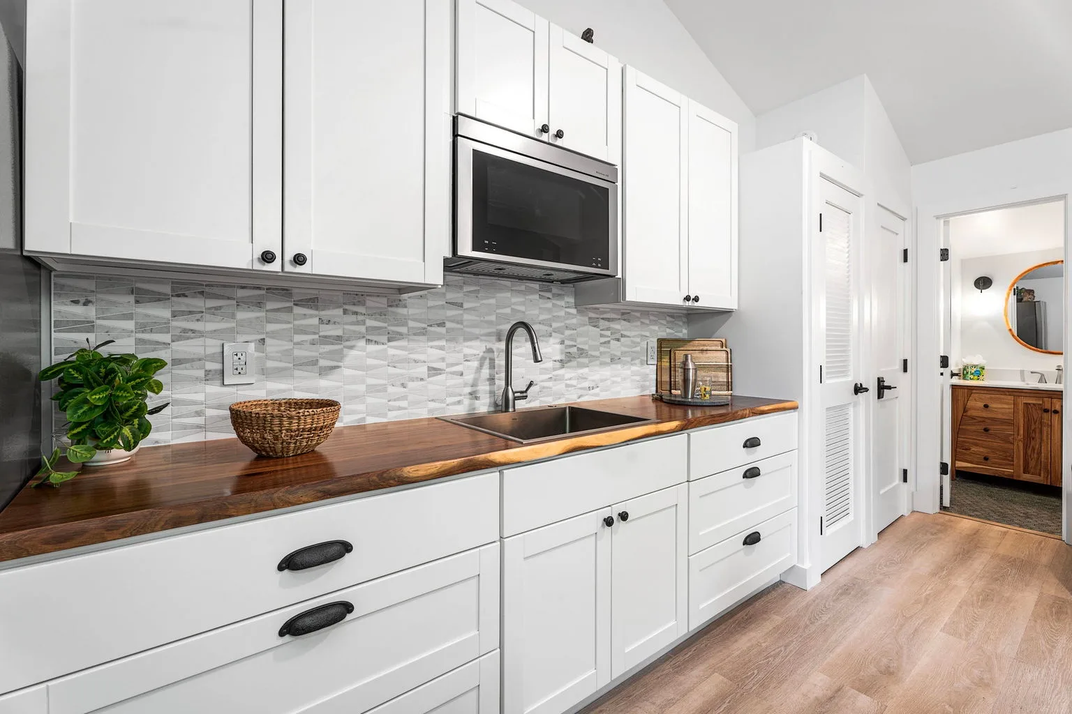 A bright kitchen with white cabinetry, a countertop, and a sink.