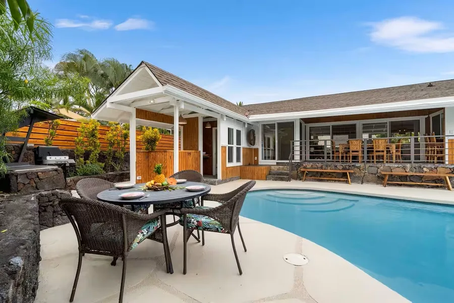 A poolside patio with outdoor seating beside a swimming pool.
