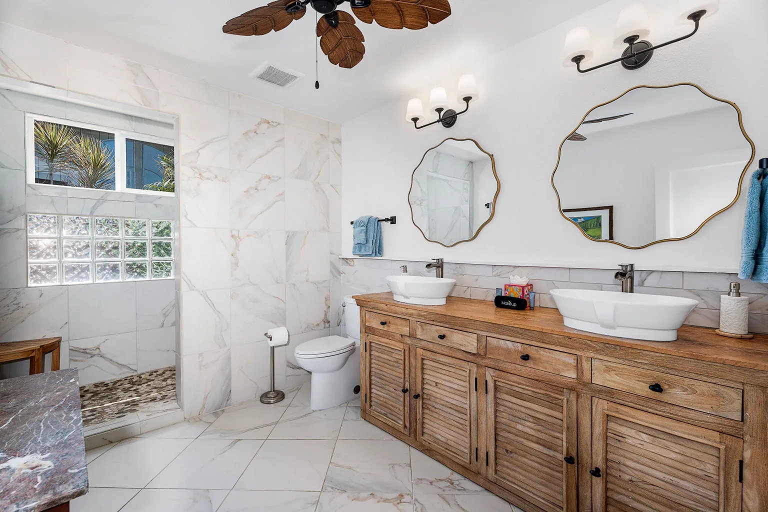 A bright bathroom with a long wooden vanity and two sinks.