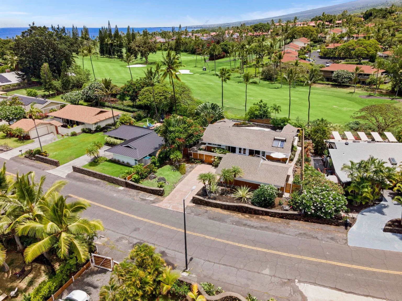 An aerial view of homes beside a broad green golf course.