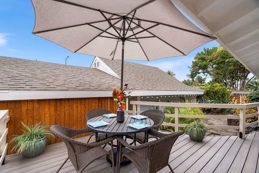 An outdoor deck dining area with a round table beneath a large umbrella.