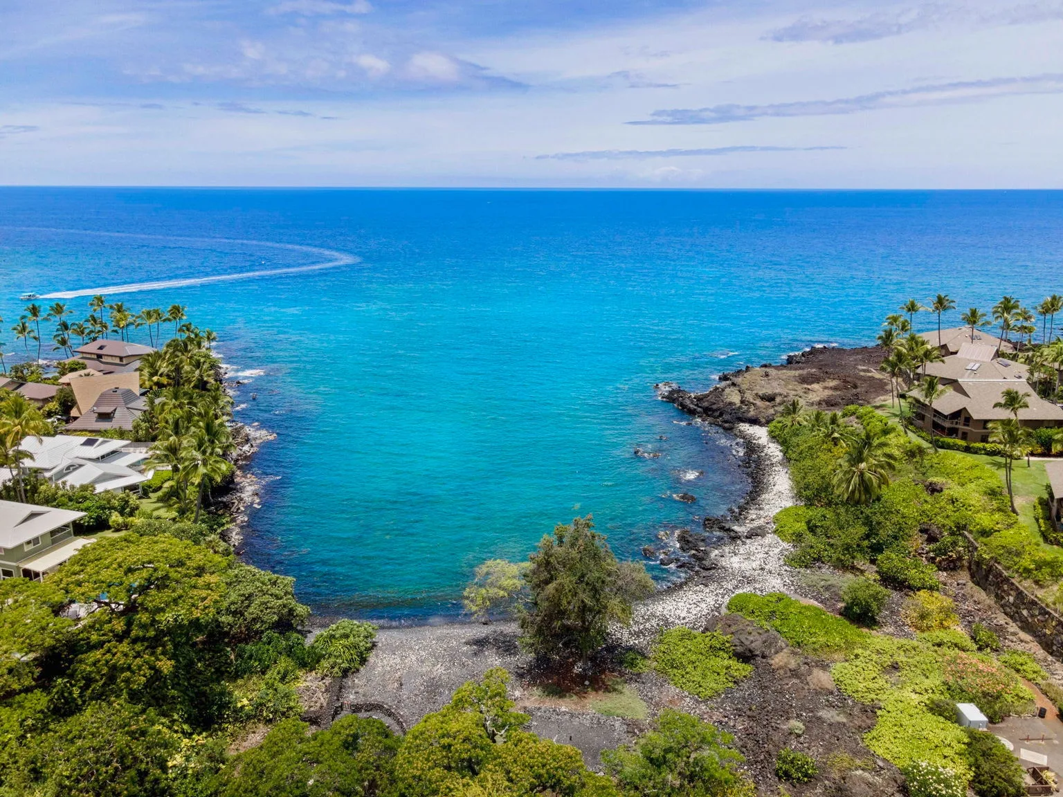 A turquoise coastal bay curves between rocky shores lined with greenery.