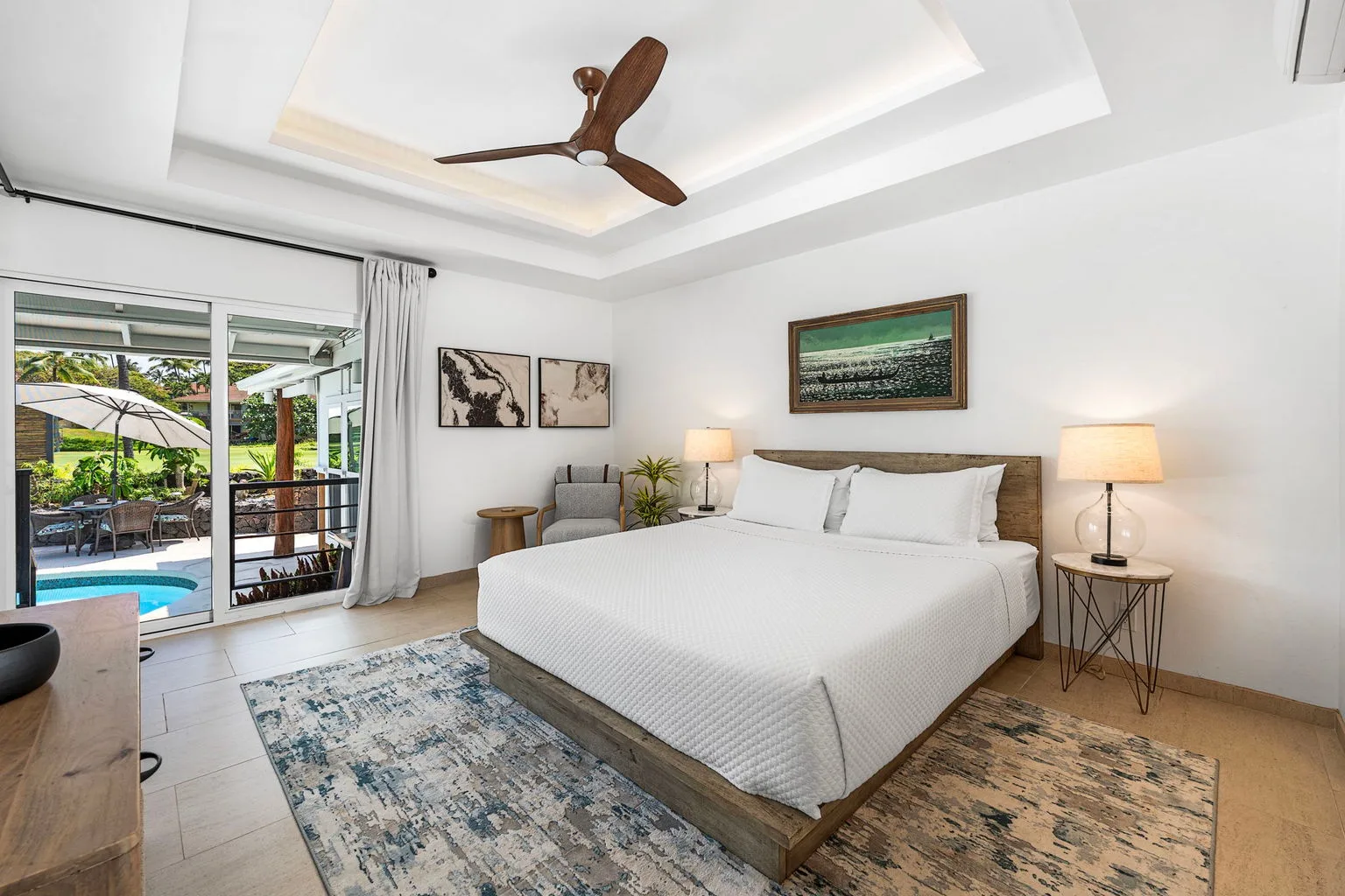 A bright bedroom with a large bed and sliding glass doors opening onto a patio.