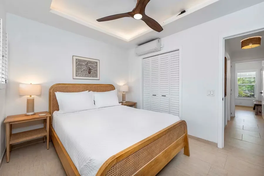 A bright bedroom with a neatly made bed and white louvered closet doors.