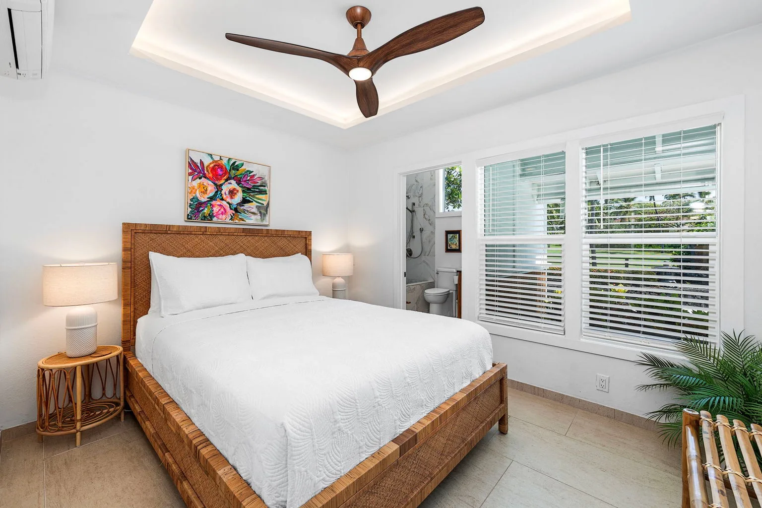 A bright bedroom with a neatly made bed and large windows.