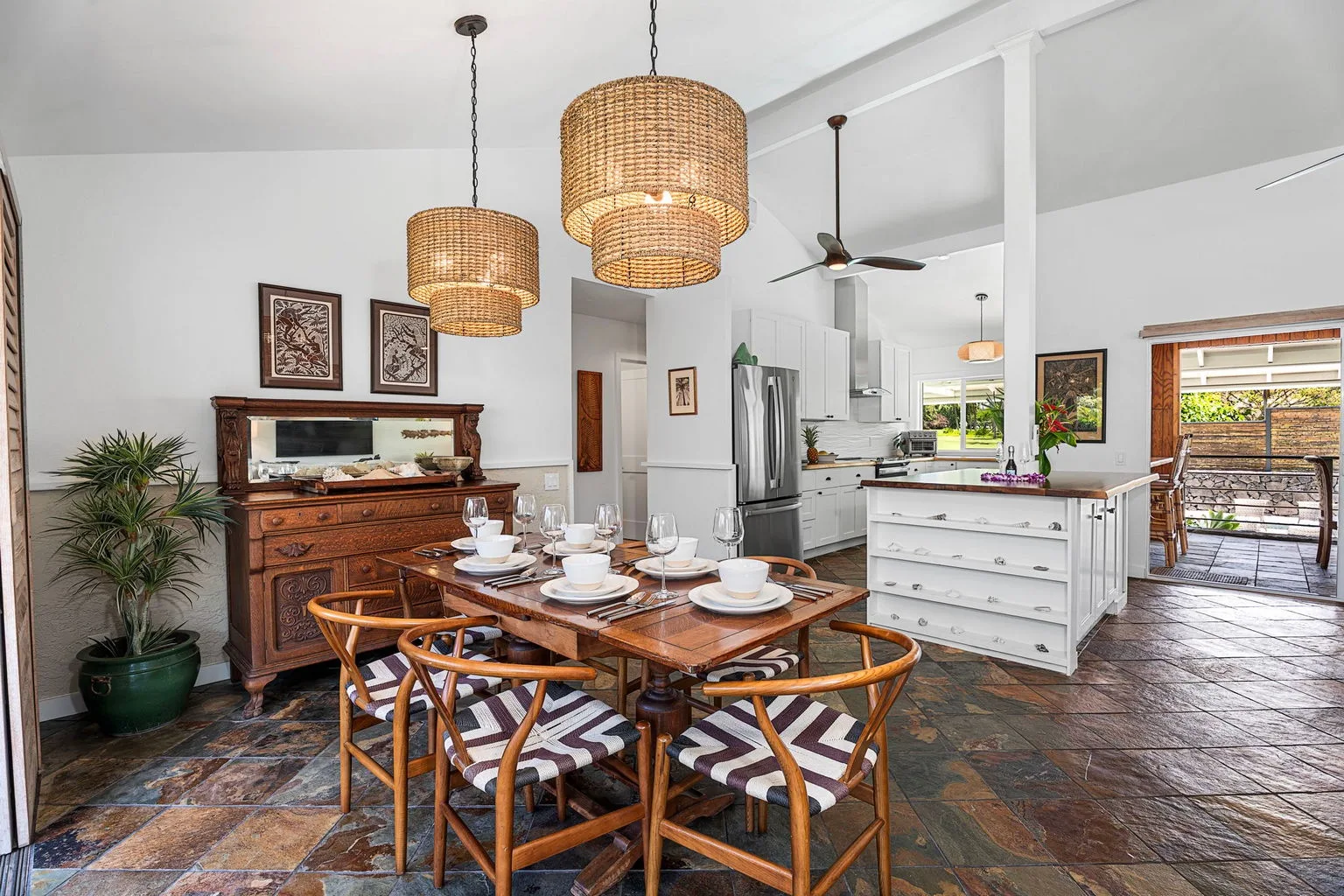 A dining area with a set table, wooden seating, and a kitchen in the background.