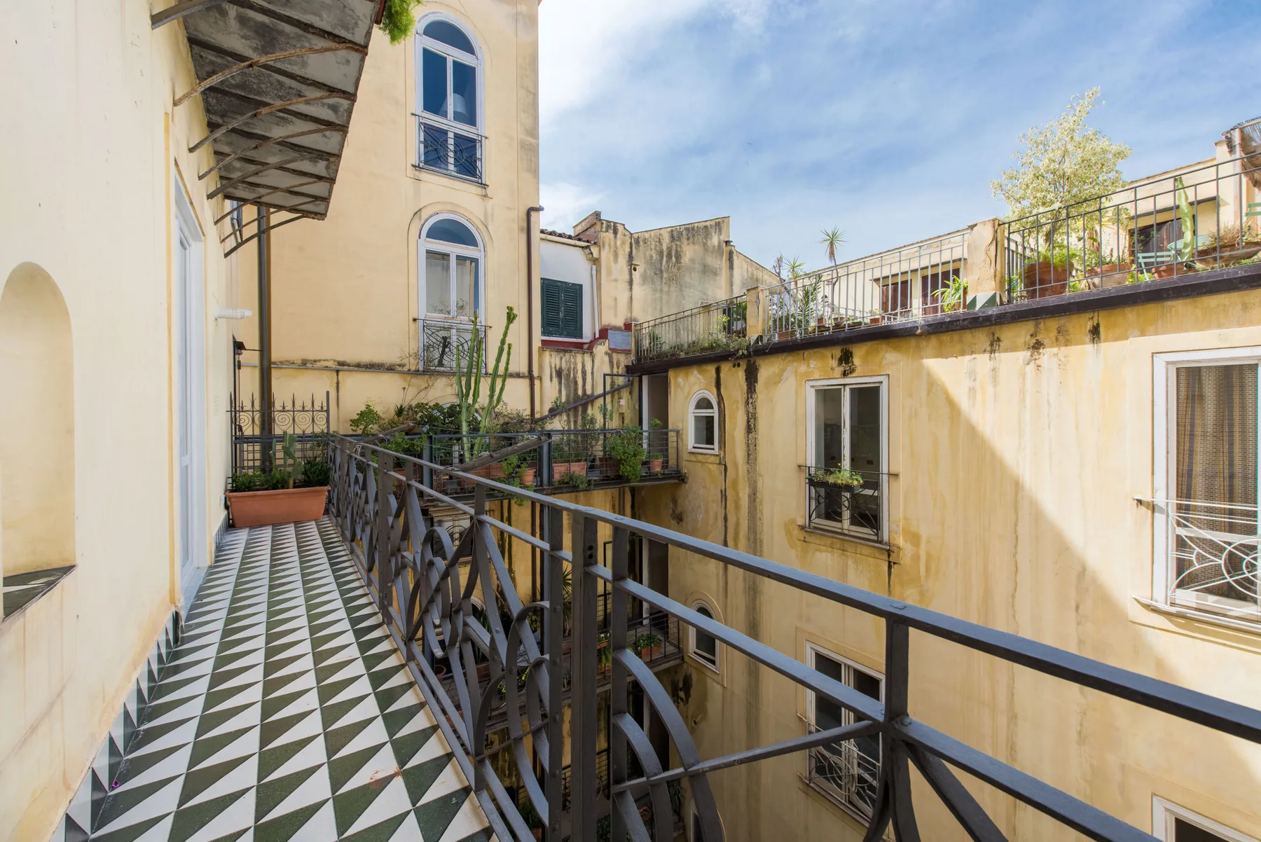 An outdoor balcony walkway overlooks a courtyard of surrounding buildings.