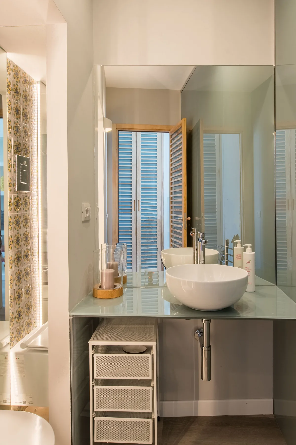 A bathroom vanity with a vessel sink and mirror beside a tiled shower.