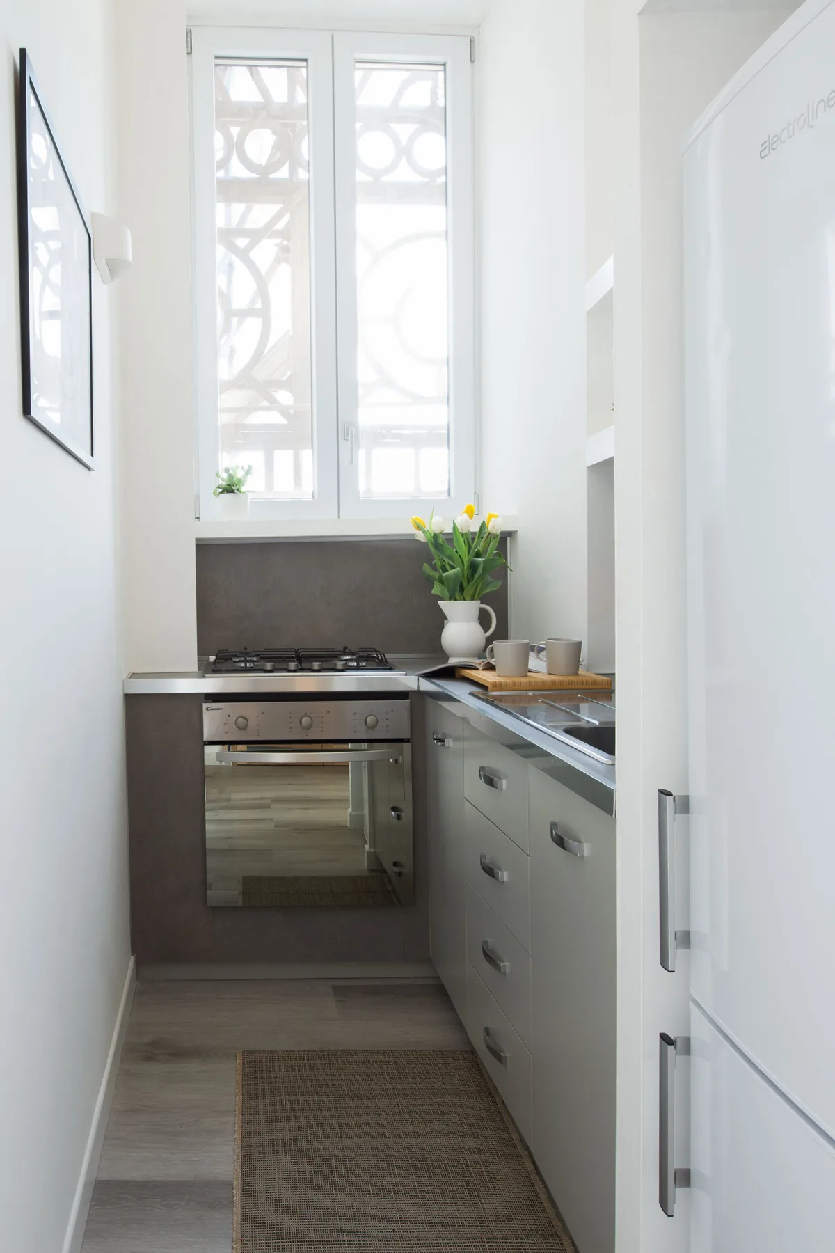 A narrow kitchen with a window, counter, and built-in oven.