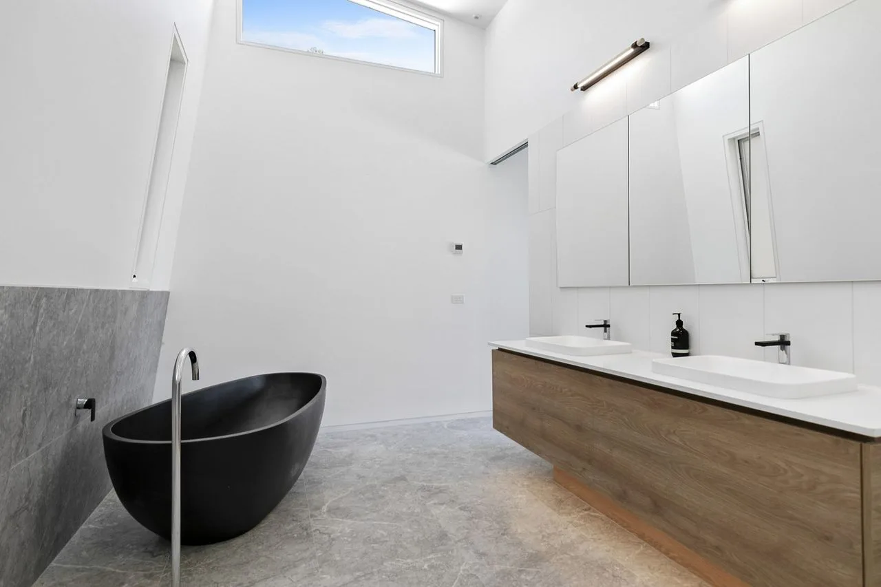 Un baño amplio con una bañera exenta y un lavabo largo.