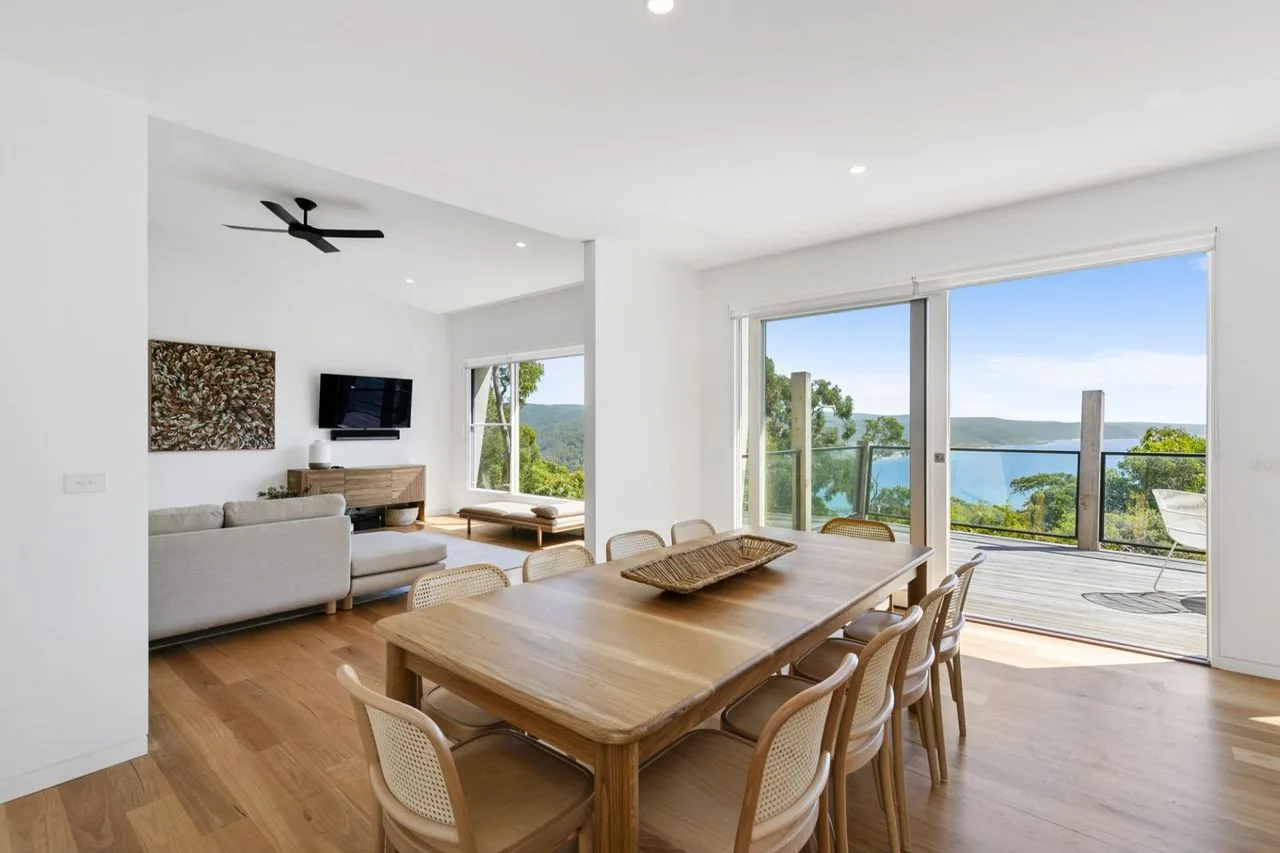 A bright dining area opens onto a deck with views of the water.