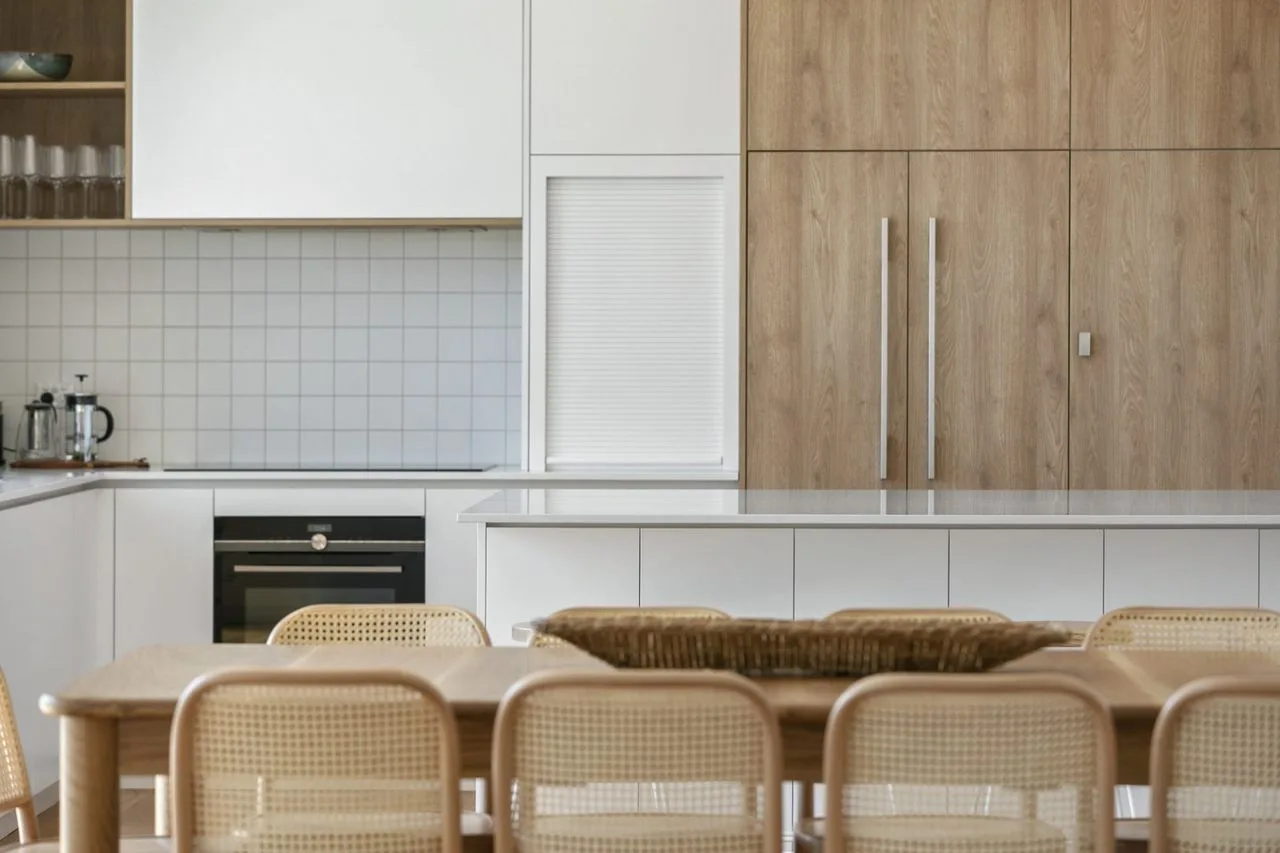 Cocina y comedor con muebles claros y asientos tejidos.