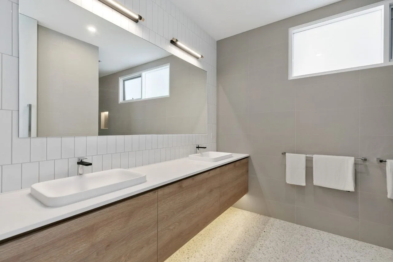 Un baño moderno con un tocador largo y un amplio espejo de pared.