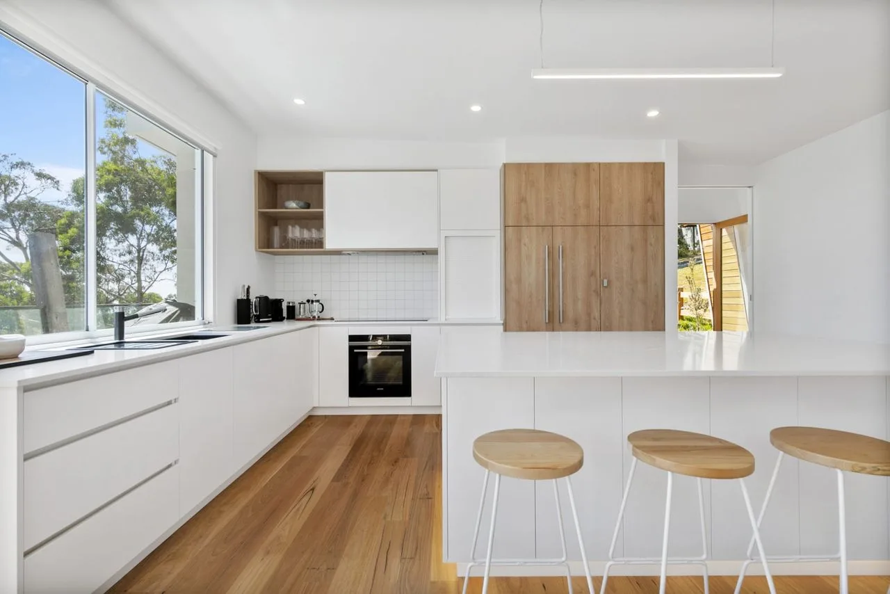 Una cocina moderna y luminosa con gabinetes blancos y una isla amplia.