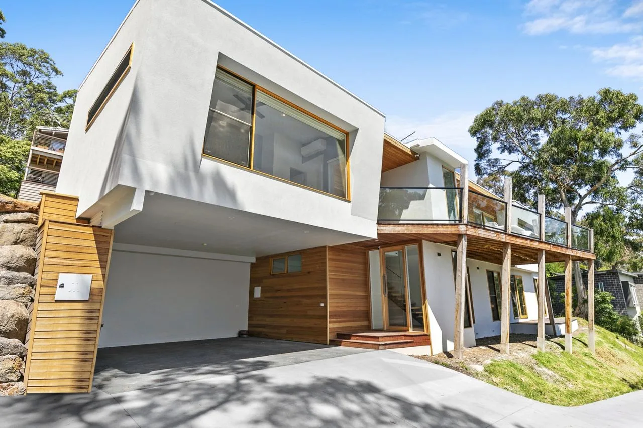Modern house exterior with a balcony overlooking the driveway.