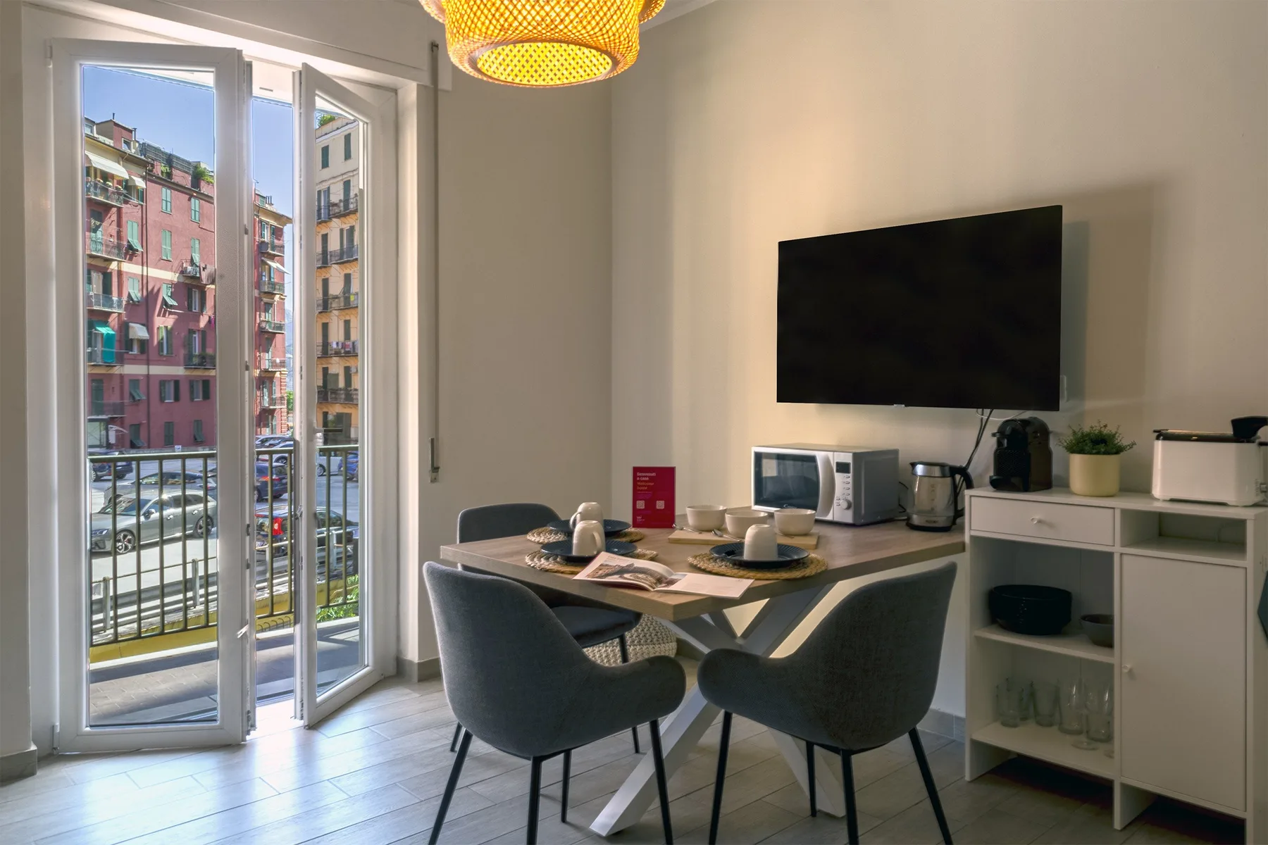 A dining area with a table and chairs beside an open balcony door.