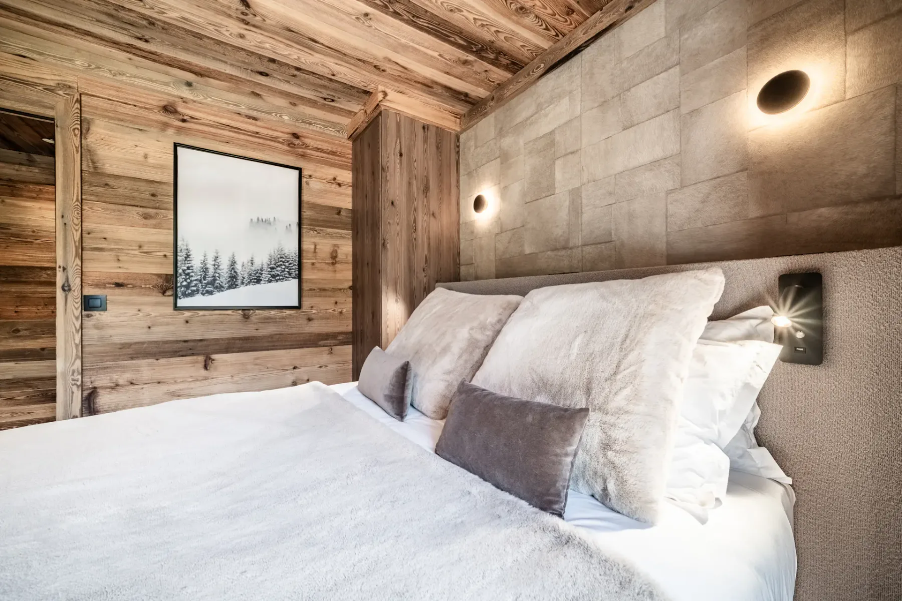 Dormitorio con una cama grande, paredes de madera y un paisaje invernal enmarcado.