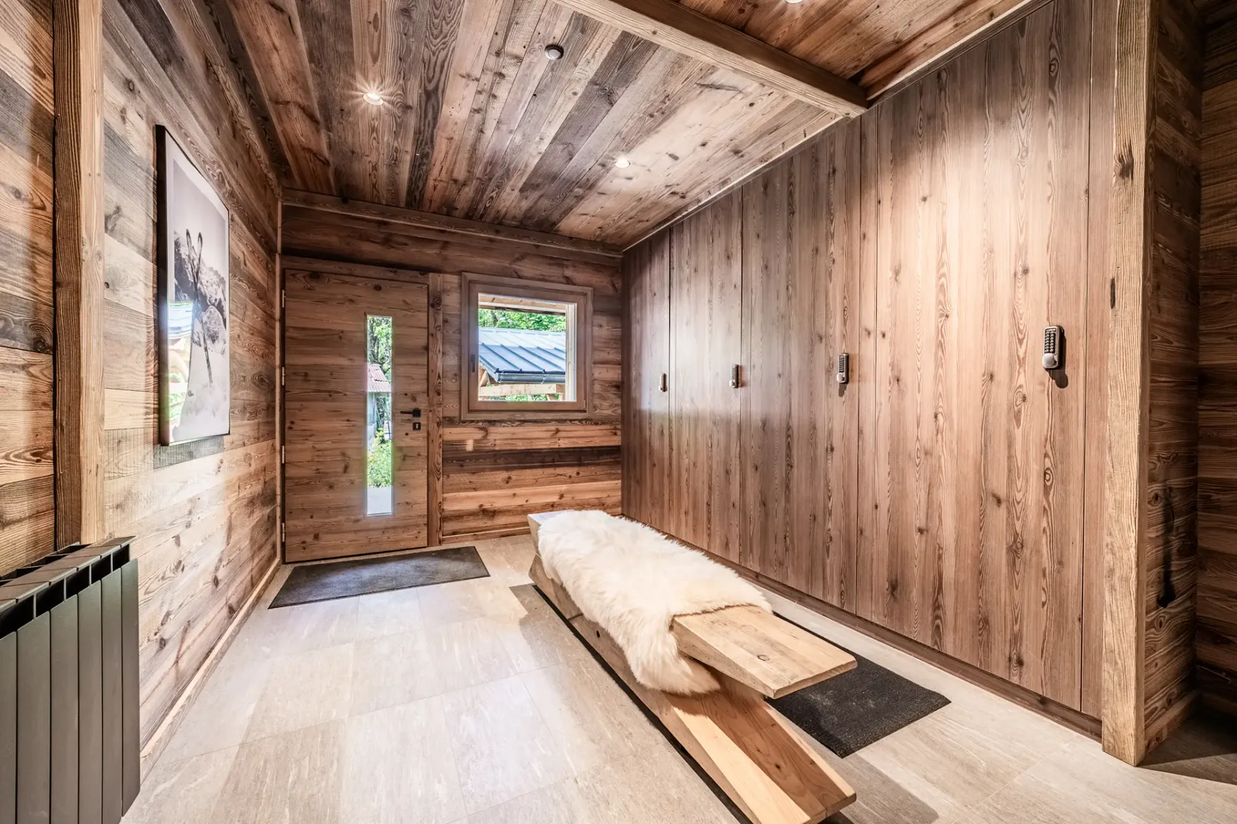 Un recibidor revestido de madera con un banco largo y ventanas junto a la puerta.