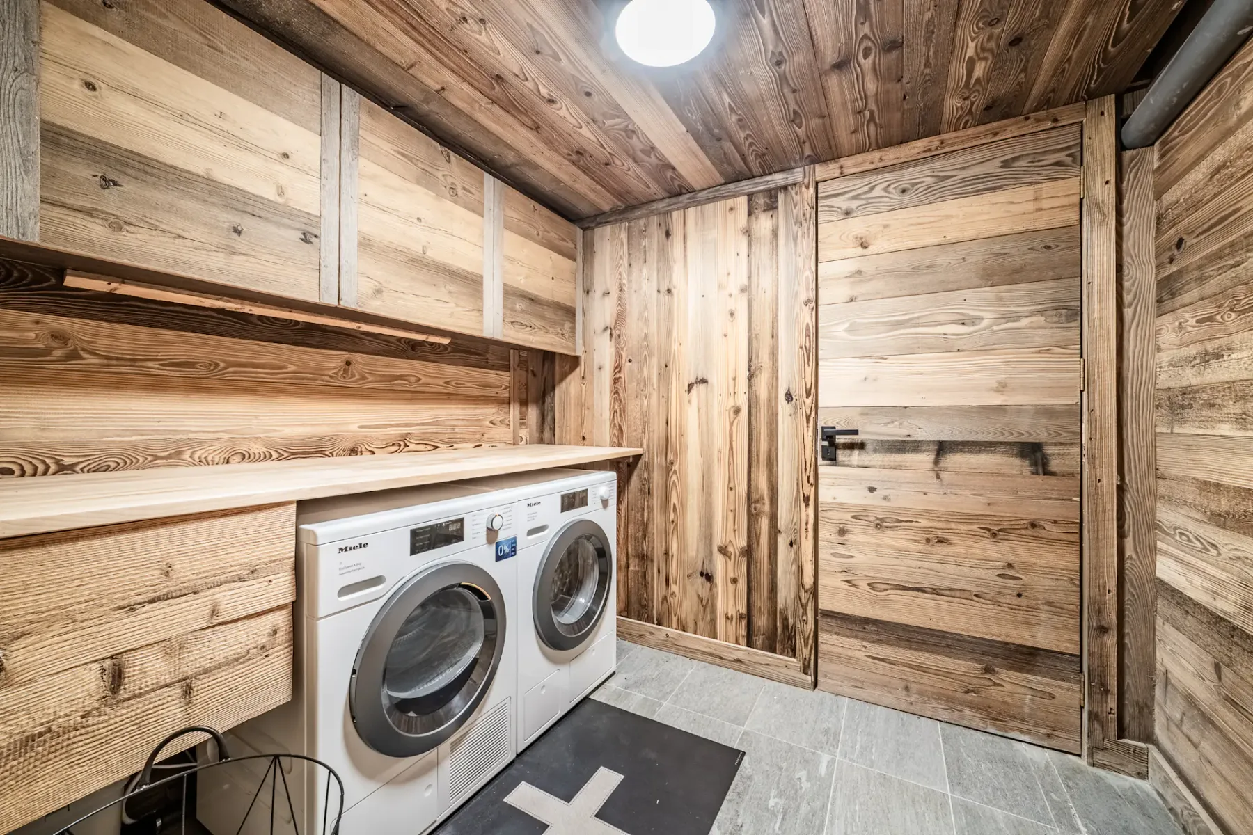 Cuarto de lavado revestido de madera, con máquinas de carga frontal y suelo de baldosas.