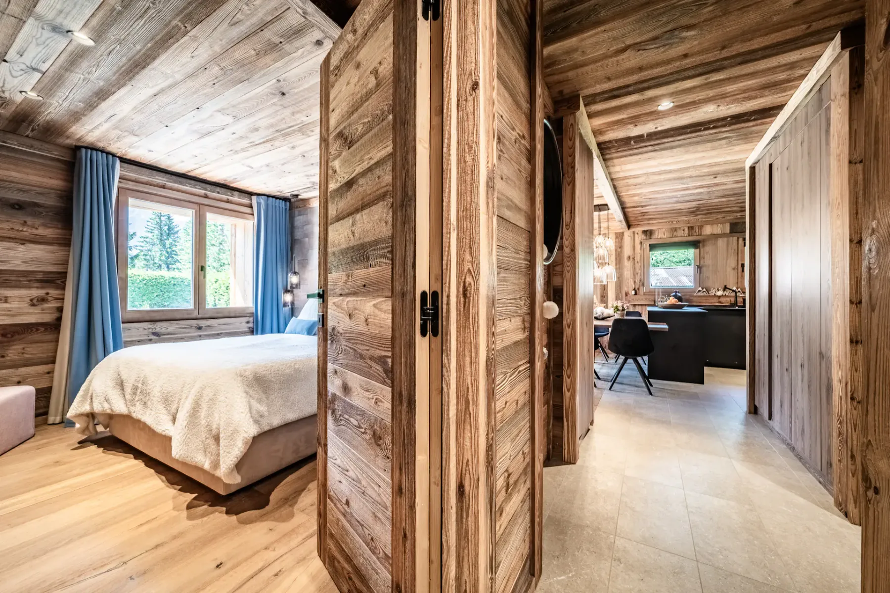Un dormitorio revestido de madera se abre a un pasillo que conduce a una cocina.