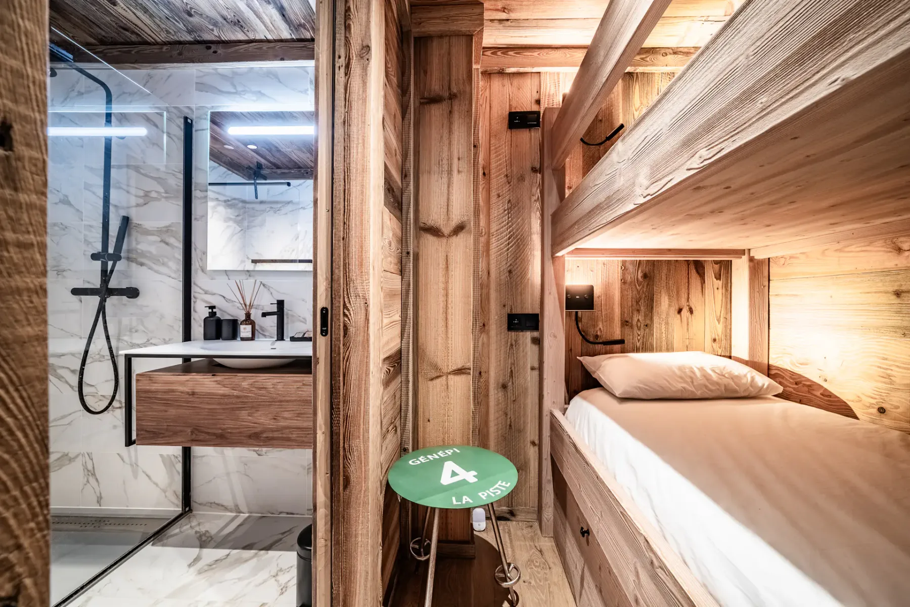 Dormitorio revestido de madera con una litera y un pequeño taburete verde al lado.