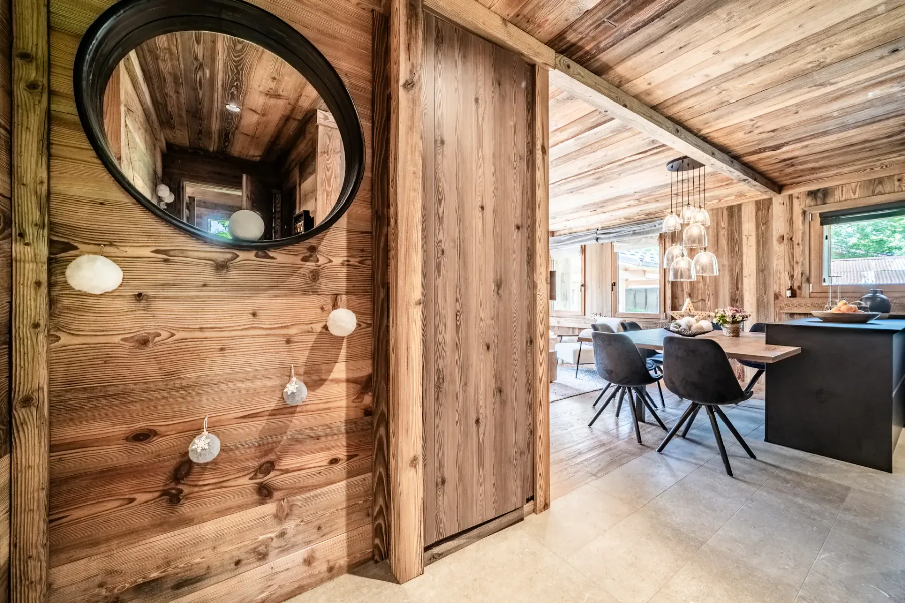 Una entrada revestida de madera da a un comedor con mesa y asientos.