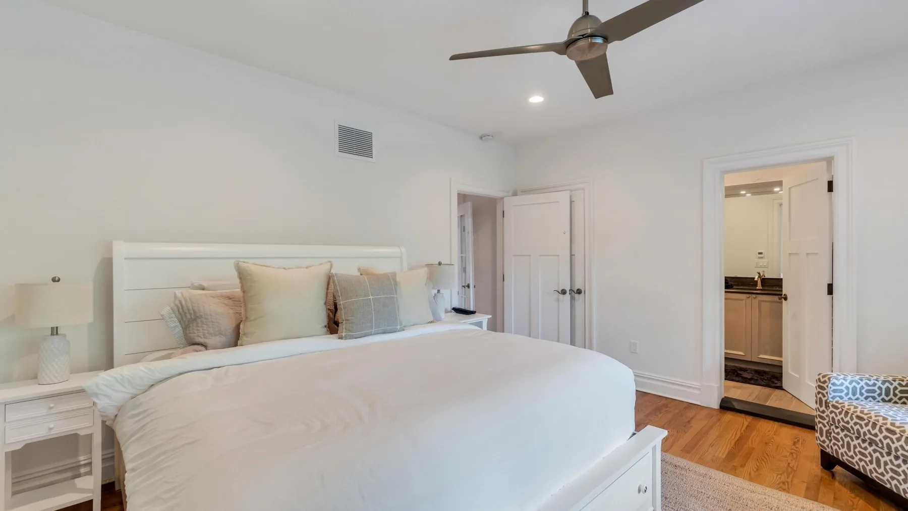 A bedroom with a neatly made bed and a doorway opening to a bathroom.