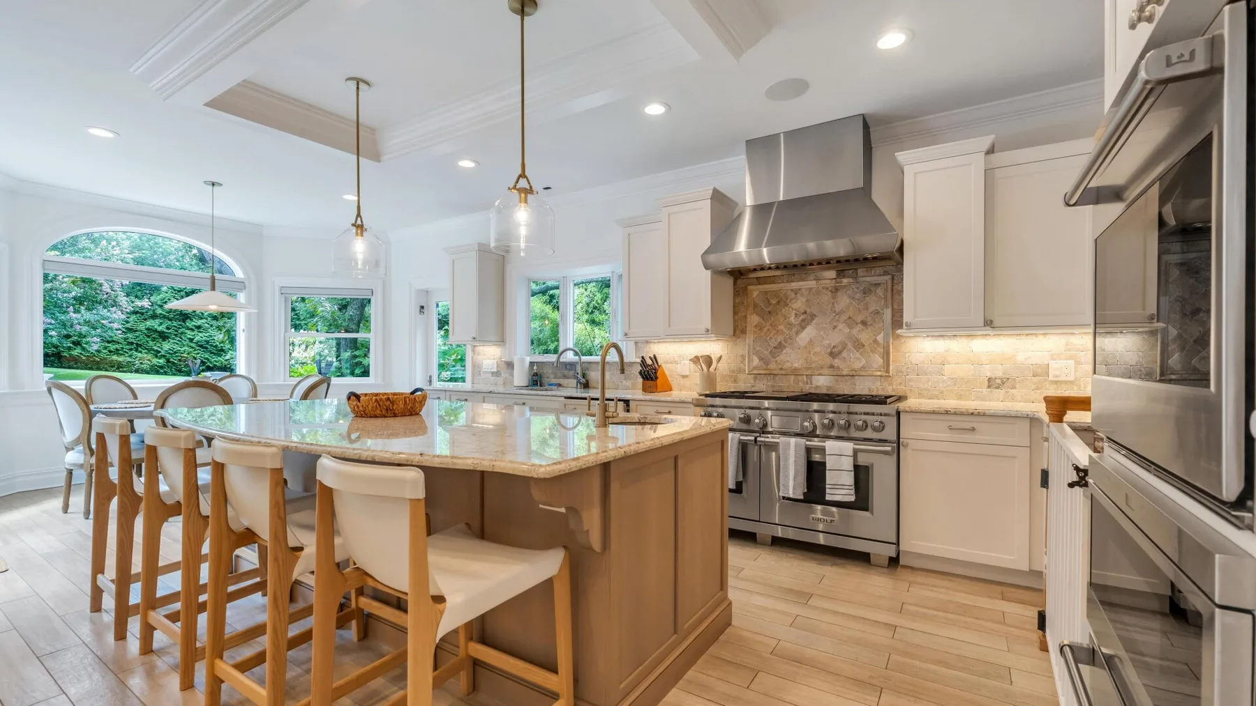 A bright kitchen with a large island, dining seating, and stainless steel appliances.