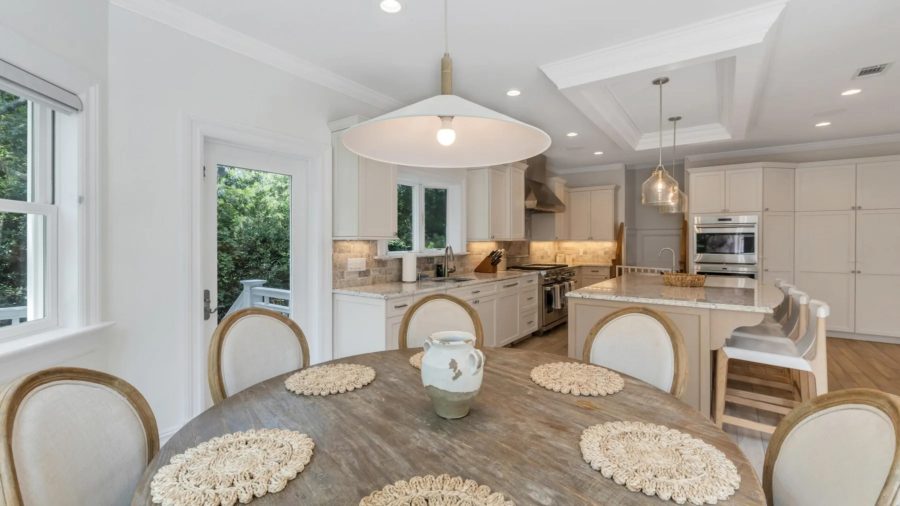 A bright open-plan kitchen and dining area with a large table and central island.