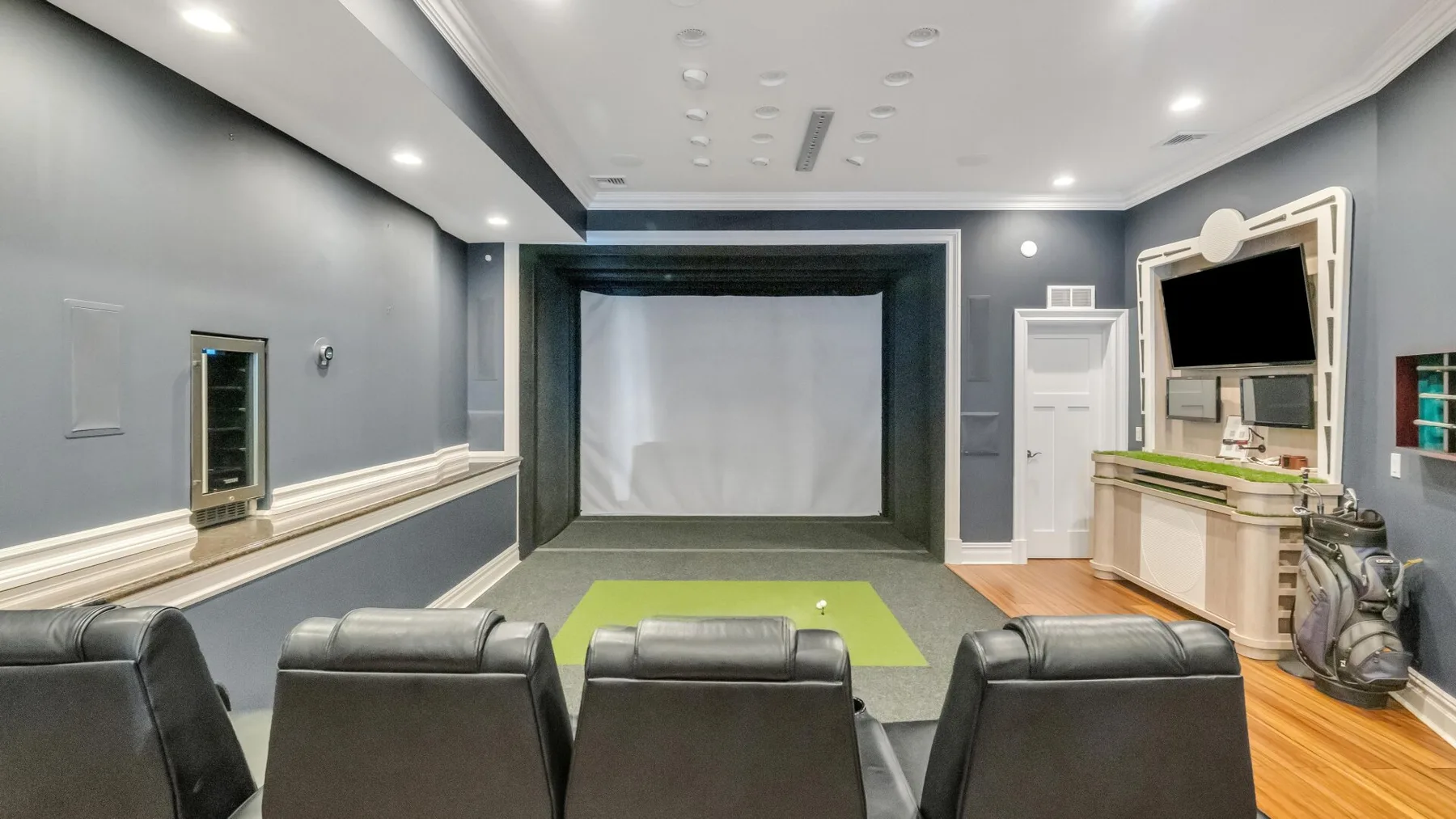A home theater room with rows of dark seating facing a large projection screen.