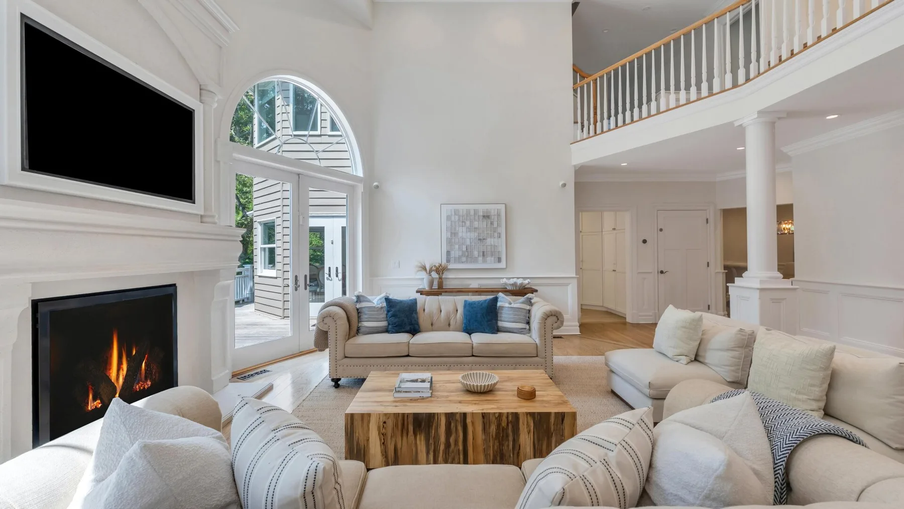 A bright living room with seating around a coffee table and a fireplace.