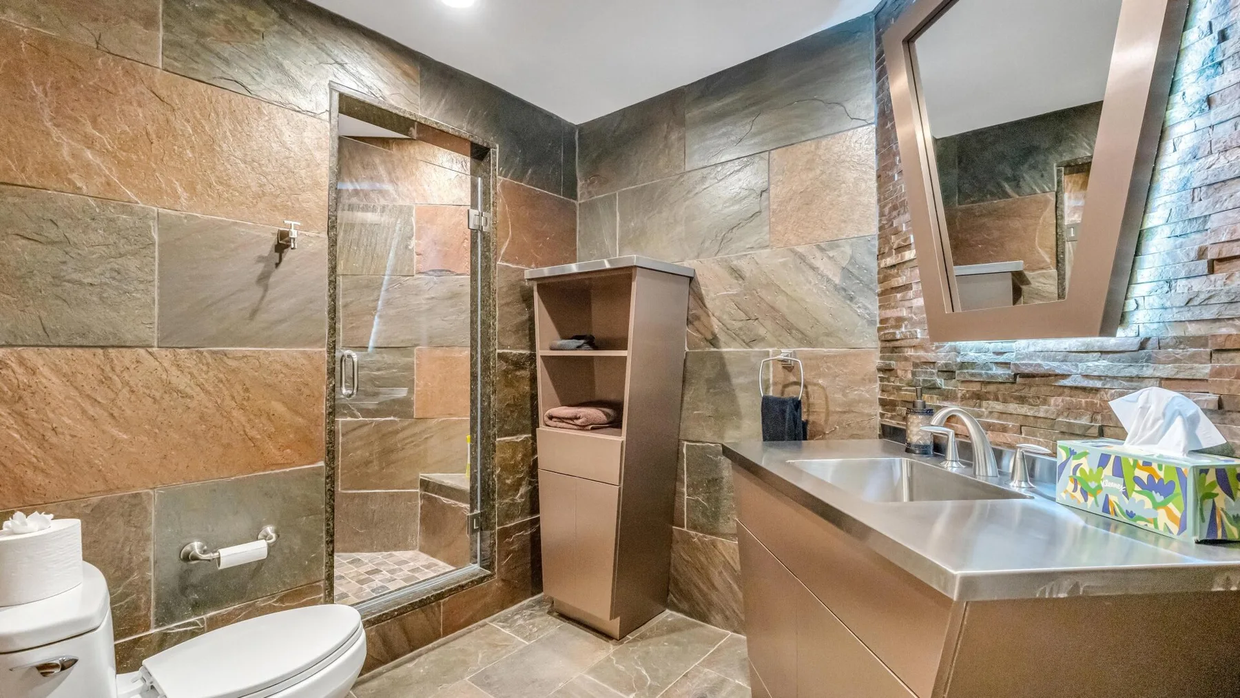 A tiled bathroom with a walk-in shower, vanity, and mirror.