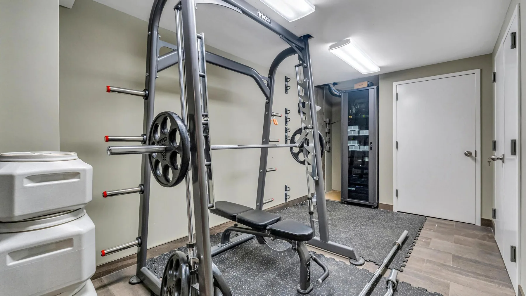 A home gym with a weight machine, bench, and storage cabinets.