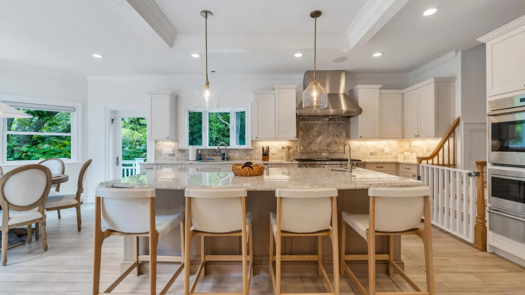 A bright kitchen with a large island and seating beneath pendant lights.