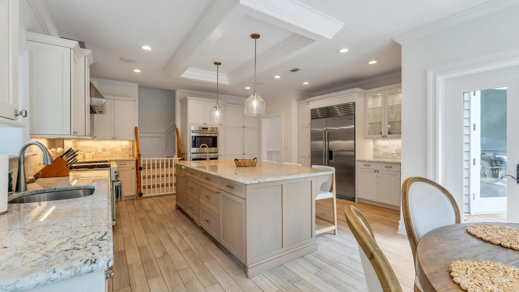 A bright kitchen with a large island, light cabinetry, and a dining table.