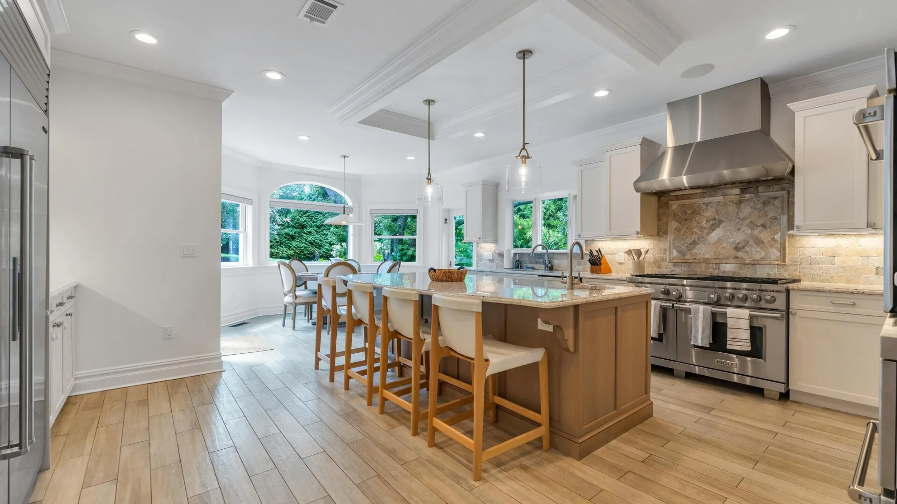 A bright open kitchen and dining area with a central island and large windows.