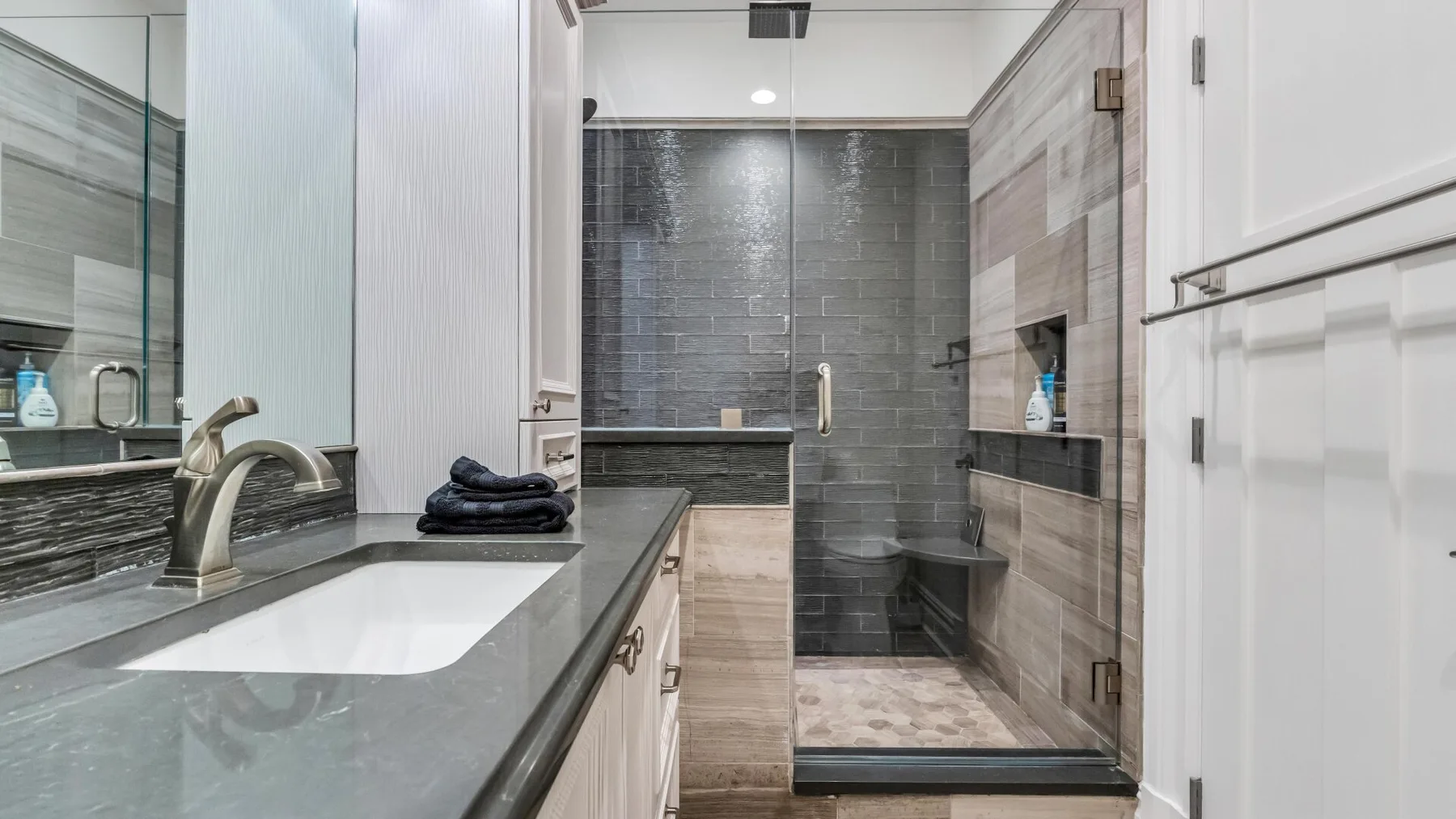 A modern bathroom with a glass shower and a wide sink counter.