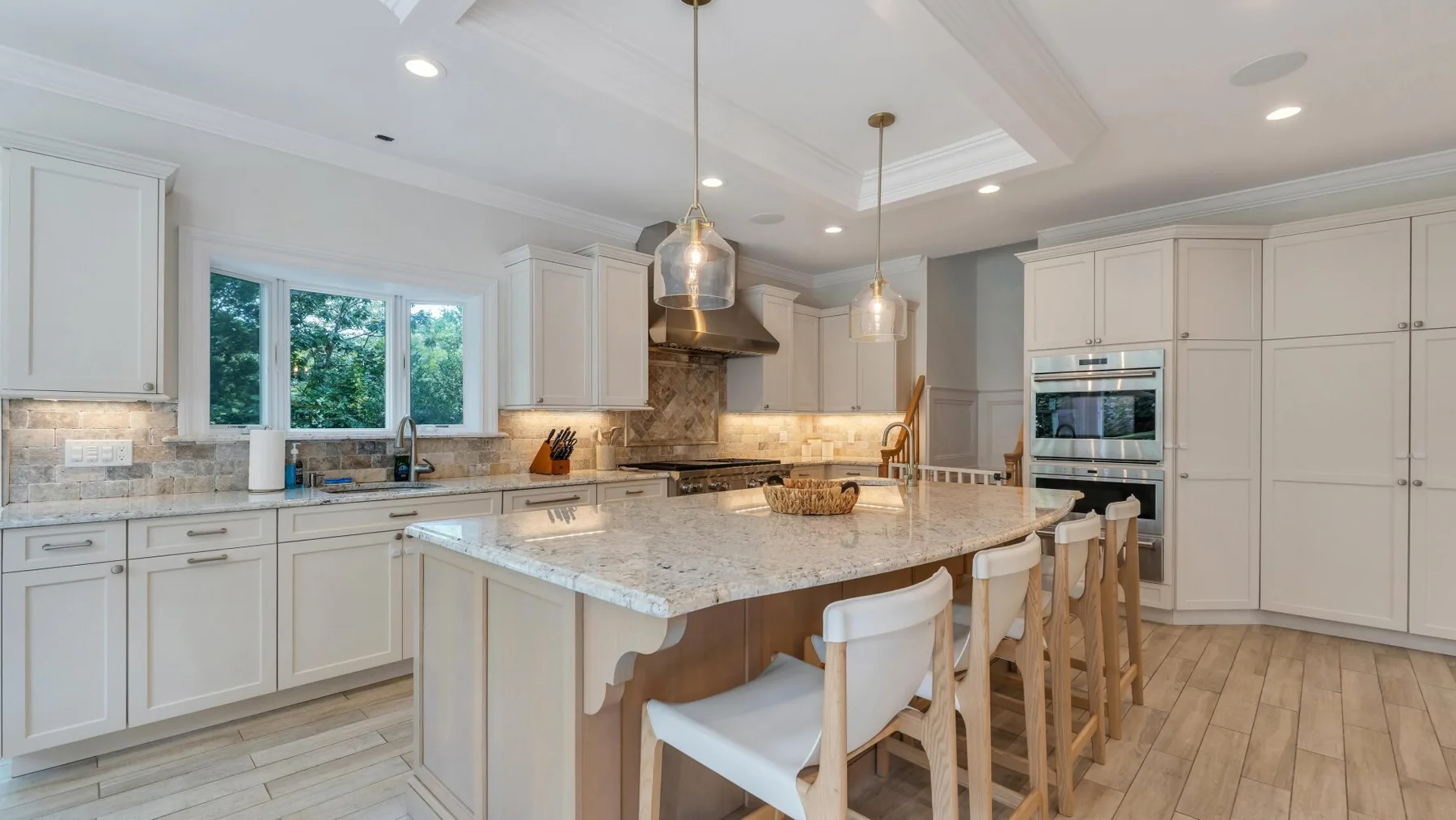 A bright kitchen with a large central island and light cabinetry.