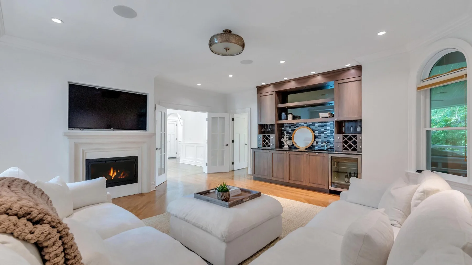 A bright living room with white seating, a fireplace, and built-in cabinetry.