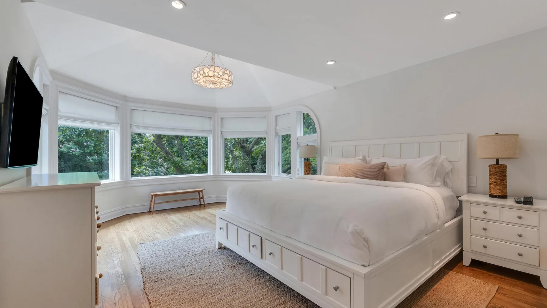A bright bedroom with a large bed and windows overlooking greenery.