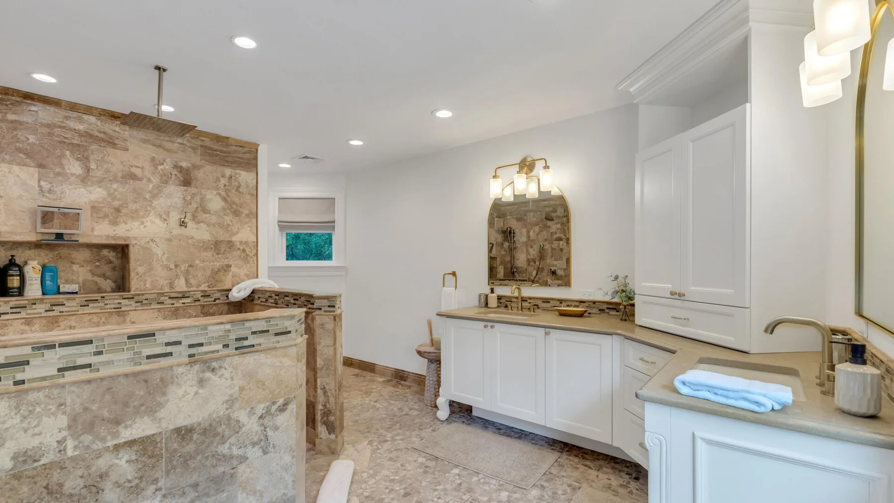 A bright bathroom with a stone-tiled shower area and white vanity.
