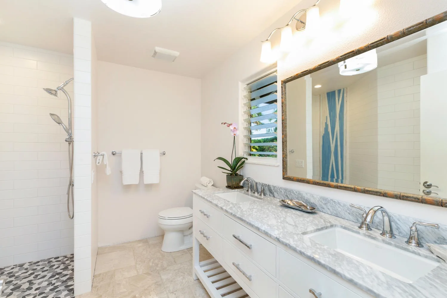 Un baño luminoso con un tocador largo, lavabo y espejo grande.