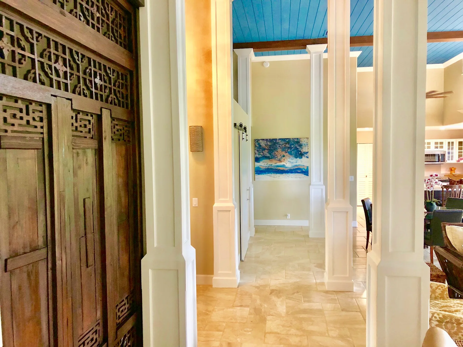Un pasillo interior luminoso con columnas altas y una celosía de madera decorativa.