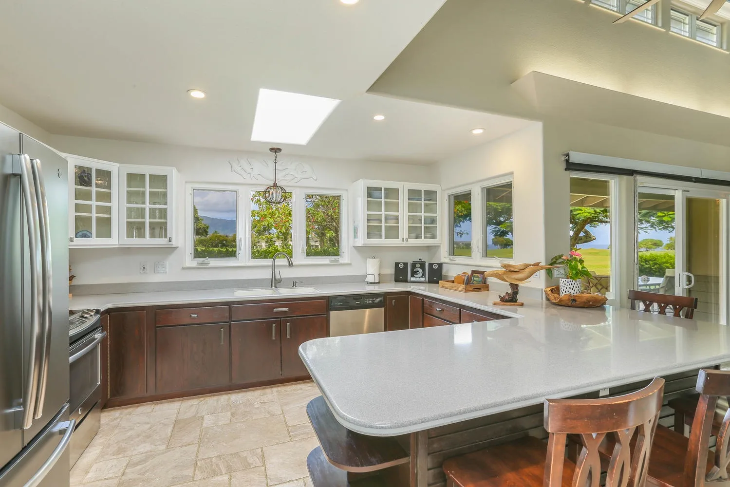 Una cocina luminosa con gabinetes de madera oscura, encimeras blancas y una isla grande.