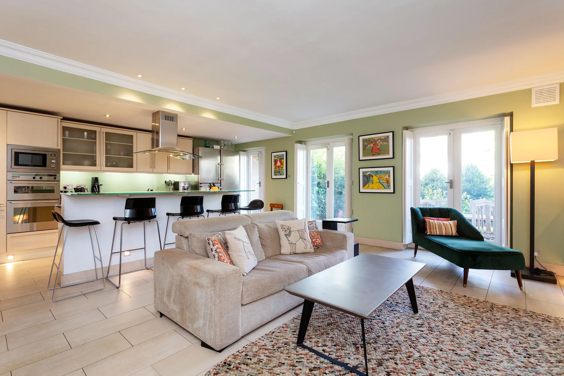 An open-plan living room and kitchen with a sofa, dining counter, and large windows.