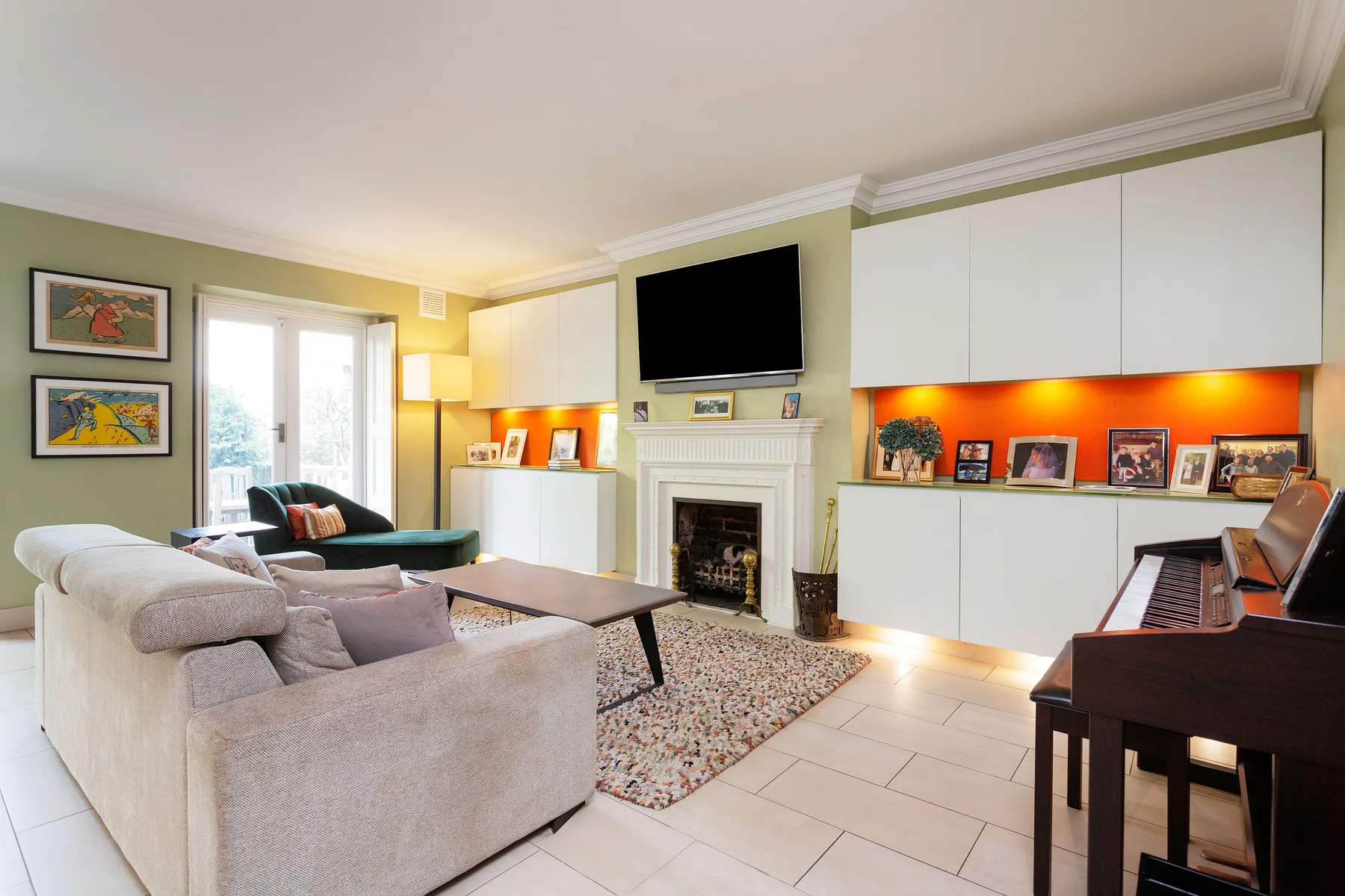 A bright living room with seating around a fireplace and a television above it.