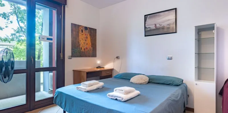 Un dormitorio con una cama cubierta con ropa de cama azul y cuadros enmarcados en la pared.
