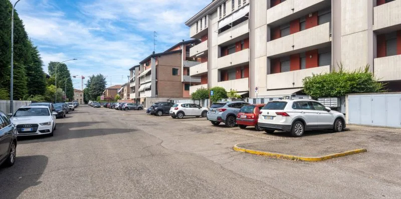 A street lined with parked cars and multi-story buildings.