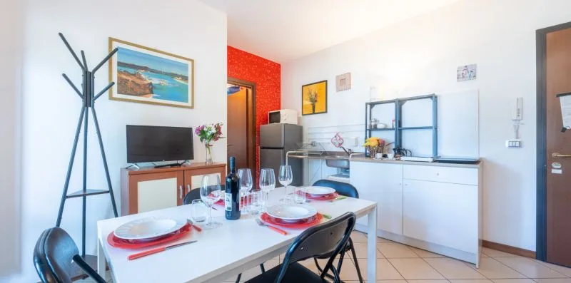 A dining area with a table and chairs beside a compact kitchen.