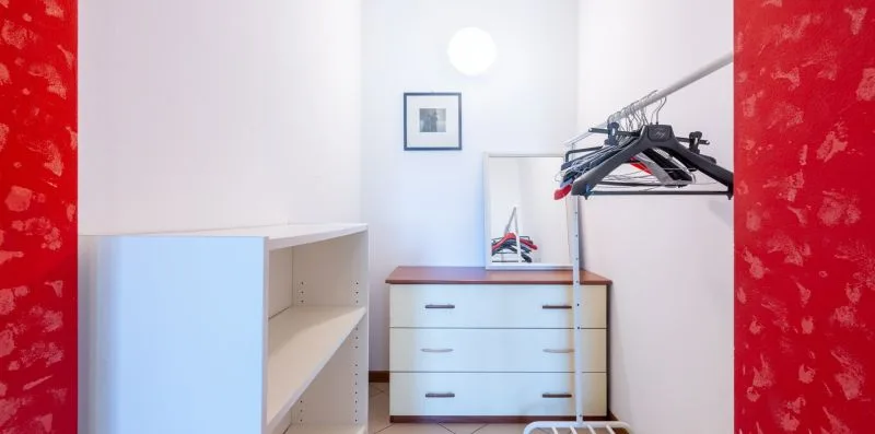 A dressing area with open shelving, a chest of drawers, and a clothes rack.